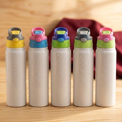 Cinco botellas infantiles blancas con tapas de colores